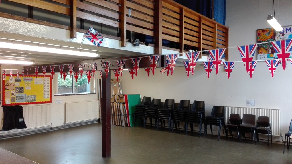 Church hall with chairs and tables stacked against a wall
